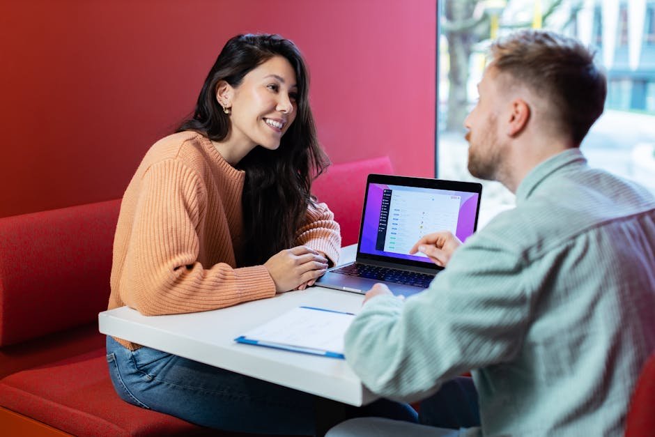 Two colleagues discussing business ideas over a laptop in a New York City cafe.